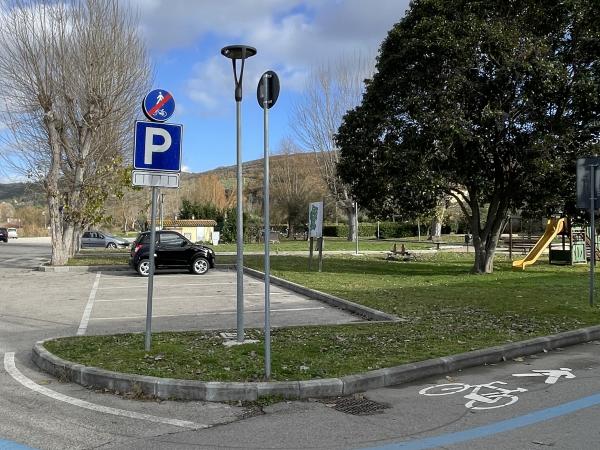 Start of path: open parking lot in Torricella, near pier and green area. Cyclo-pedestrian end sign. Paved path.